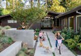 A garden with mature perennial garden beds surrounded by a concrete-walled courtyard.