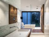 In the master bath, a custom raised Silestone sink is surrounded by a teak countertop and Porcelanosa glass tiles. Teak slats anchor the glass-enclosed shower.