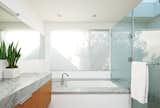 The minimalist bathroom boasts Cararra marble surfaces, Hansgrohe faucets and shower fixtures, and a skylight by Velux.