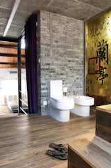 A yellow glass panel divides the shower from the toilet and the bidet.