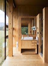 The raw pine that wraps around the vanity, walls, flooring and ceiling in the bath lends texture and warmth.