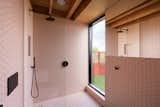 Pink hexagonal tiles line the walls and floor in the bathroom, which has a large glass shower.
