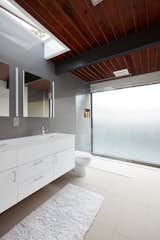 The home’s bathrooms feature Lacava undermount sinks, Hansgrohe fixtures, and Duravit toilets. Natural light filters in through a skylight above the vanity.