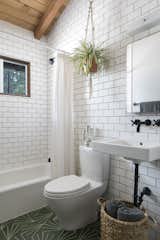 The luminous new bathroom repurposes the original medicine cabinet and light fixture, while statement cement floor tile from Original Mission Tile in Hex Bakery adds a graphic punch. The ceramic subway wall tile is Florida Tile ‘Arctic Matte’, and the wall-mounted faucet is a Tiburon Series Lavatory Faucet from California Faucets in matte black.