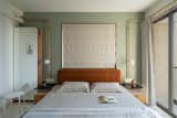 The master bedroom's wall-mounted light sconces continue upward to form the curtain rods.