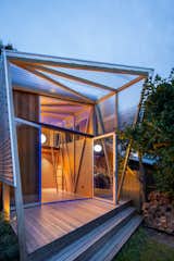 A pergola made of opaque, corrugated polycarbonate extends from the front facade and guards against bright sunlight, wind, and rain. 