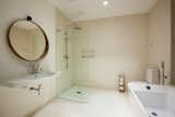 The minimalist bathroom design features an open shower and a freestanding tub.