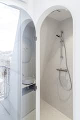 The bathroom features light grey tiles, a shower, sink, and toilet.