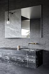 These Sekhia bathroom wall tiles are a Japanese product from Inax. The sink vanity is made from black Marquina marble, and the aged bronze faucets are from Brodware.