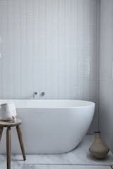 A ceramic soaking tub is paired with an antique wooden stool found in a local market.