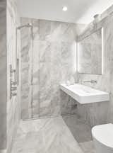 The private bathroom features a wetroom style open enclsoure, linear drain,Quartzite tile, and a concealed mirrored medicine cabinet. The fixtures are by Fantini.
