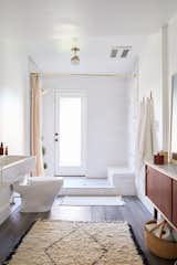 Modern elements blend with rustic materials in the bath, including an open tile shower, marble step, and brass ceiling light from Cedar + Moss.
