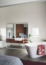 The master suite follows an open concept with the bath open to the sleeping area. A freestanding tub pairs with a wood-and-Corian vanity.