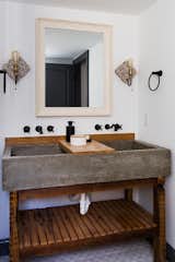 The double vanity in the master bath has a concrete trough sink with a wood slab counter.

