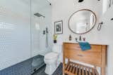 The guest bath pairs black limestone picket floors from Floor and Décor with white porcelain picket from Floor and Décor for the shower walls. The vanity is by Sage Hill Designs, and the round mirror is from Hayneedle.
