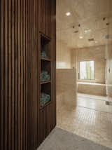 A glimpse inside the limestone-clad steam shower in the master suite. The walnut slat walls hide storage with cubbies for towels.
