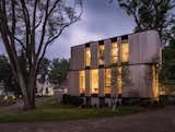 The domino-like residential volumes are staggered on top of each other and feature deeply recessed checkerboard-patterned windows to reduce glare and solar gain. The pavilion is clad in cedar to complement the adjacent stone barn, as well as the property’s heirloom trees.