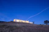 The long, low home sits unobtrusively atop the ridge. Large areas of glazing open the home to the landscape to the south.