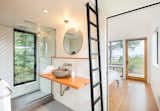 Each cabin’s bathroom has a private toilet room, sink, and shower with a floor-to-ceiling window that can be opened while showering to let nature inside. “You can literally bathe in nature,” says designer Taylor Bode. A ladder leads to a loft with a skylight. 