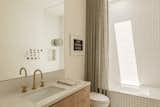 The guest bathroom features Silver Ice quartzite surfaces, which match those in the kitchen. A decorative shower curtain, rather than a glass barrier, softens the space and adds texture.
