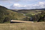 The sod roof is angled to create a sweeping elevation on approach and is planted with grass tussocks cut from the hillside during construction. “The tussocks camouflage the house, melting it into the landscape,” explains architect Kate Brown.