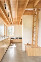 The plinth for the ladder to the sleeping loft in the primary bedroom building doubles as a bench for putting on shoes. Storage along the wall becomes a desk and a window seat nestles into an intimate corner.  