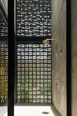 A wall of breeze block open to the elements and sun from a skylight create a sort of outdoor shower inside the bathroom off the main bedroom.  
