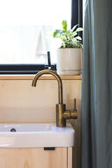 In the bathroom, an Astra Walker fixture with a bronze finish lends an elegant quality that offsets the organic texture of the plywood vanity.